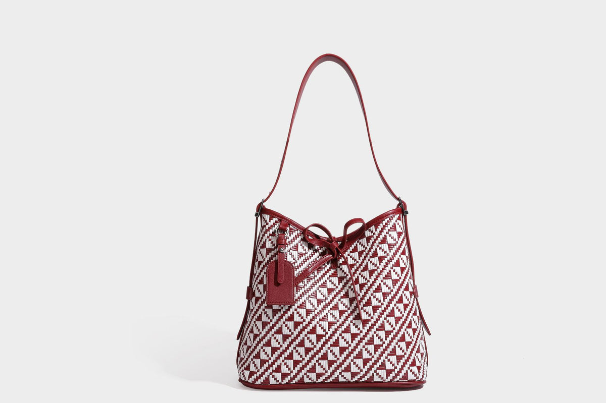 Woven geometric bucket shoulder bag in white and dark brown two-tone pattern with leather-look trim and drawstring top