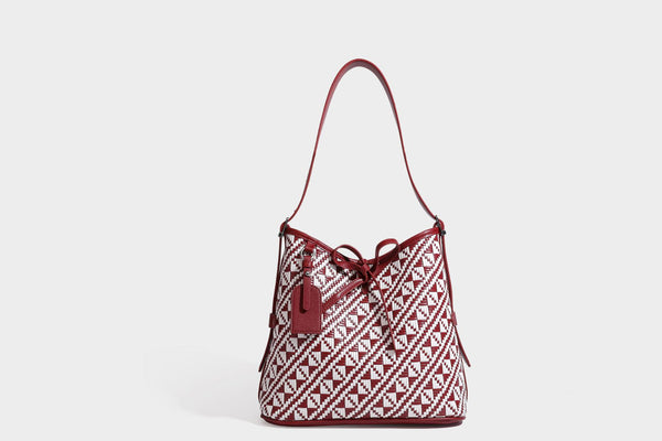 Woven geometric bucket shoulder bag in white and dark brown two-tone pattern with leather-look trim and drawstring top