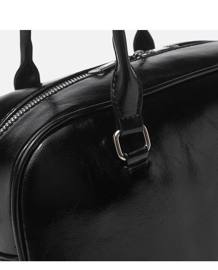 Structured glossy leather-look bowling shoulder bag with two front flap pockets, top zip closure, and long double shoulder