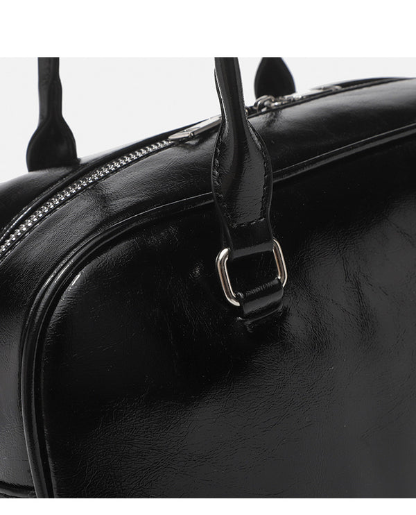 Structured glossy leather-look bowling shoulder bag with two front flap pockets, top zip closure, and long double shoulder