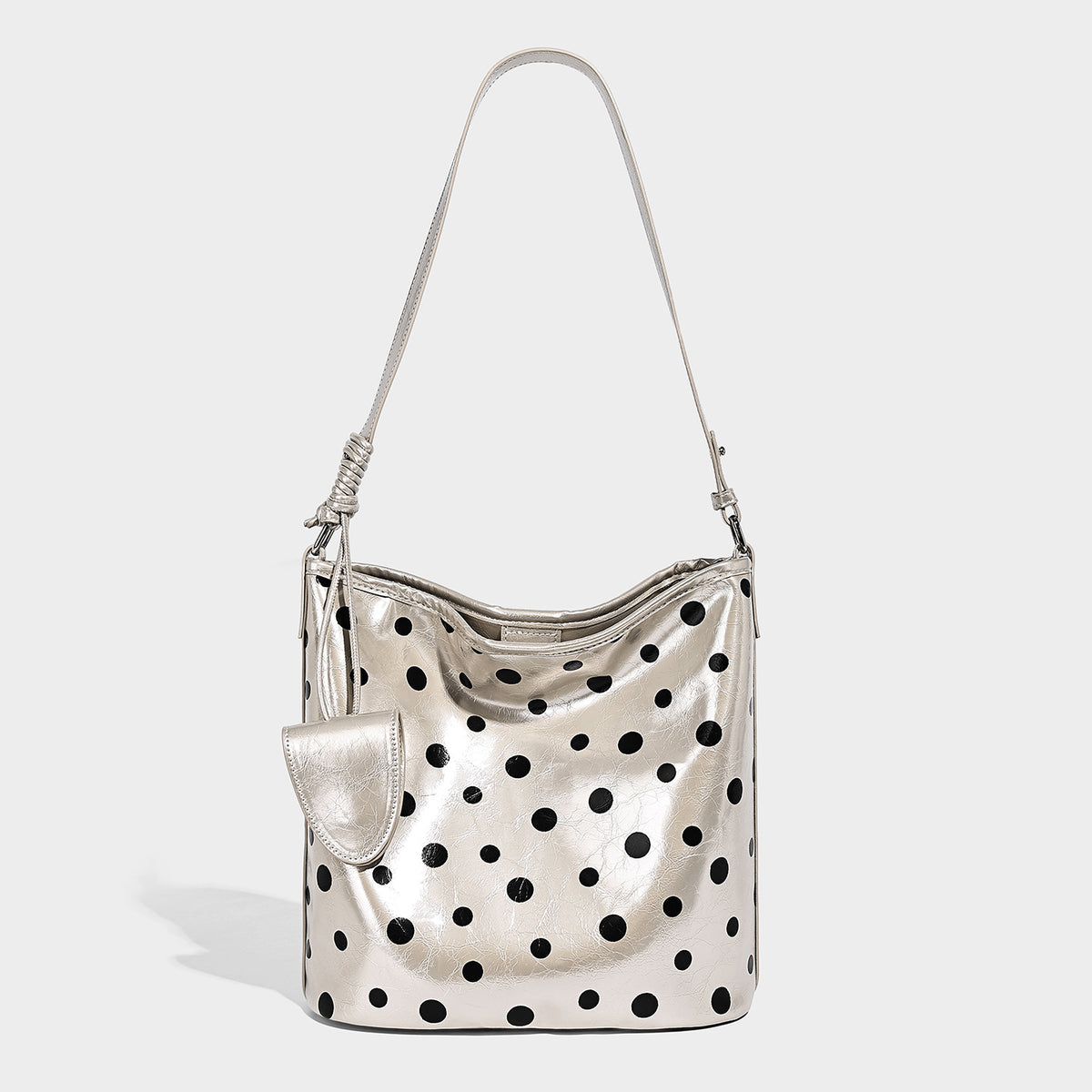 Glänzende schwarze Schultertasche im Bucket-Stil mit weißen Tupfen, langem verstellbarem Riemen und Kordelzugverschluss, Detailansicht 4
