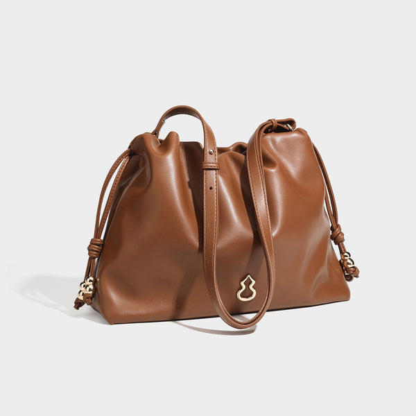 Slouchy ruched drawstring shoulder bag in smooth leather-look finish with gold-tone emblem and slim adjustable strap, detail