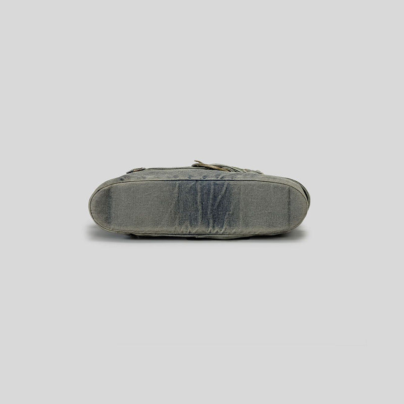 Washed blue-gray denim slouchy hobo shoulder bag with wide grommeted belt panel, brass-tone D-ring buckle, exterior zip