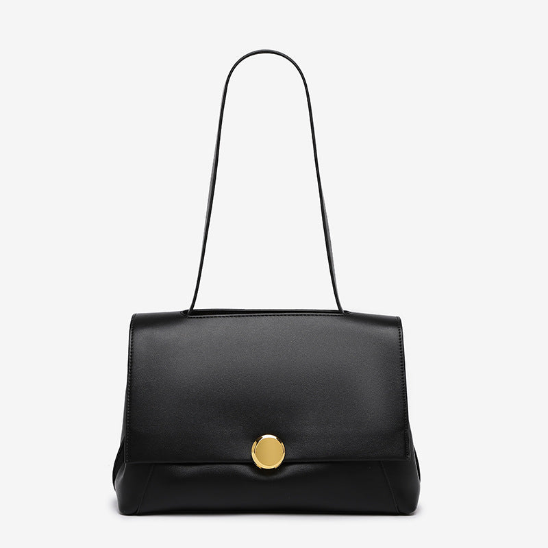 Structured flap shoulder bag with round gold-tone clasp and long flat strap in smooth matte leather-look finish, detail view