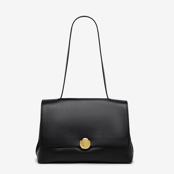 Structured flap shoulder bag with round gold-tone clasp and long flat strap in smooth matte leather-look finish, detail view