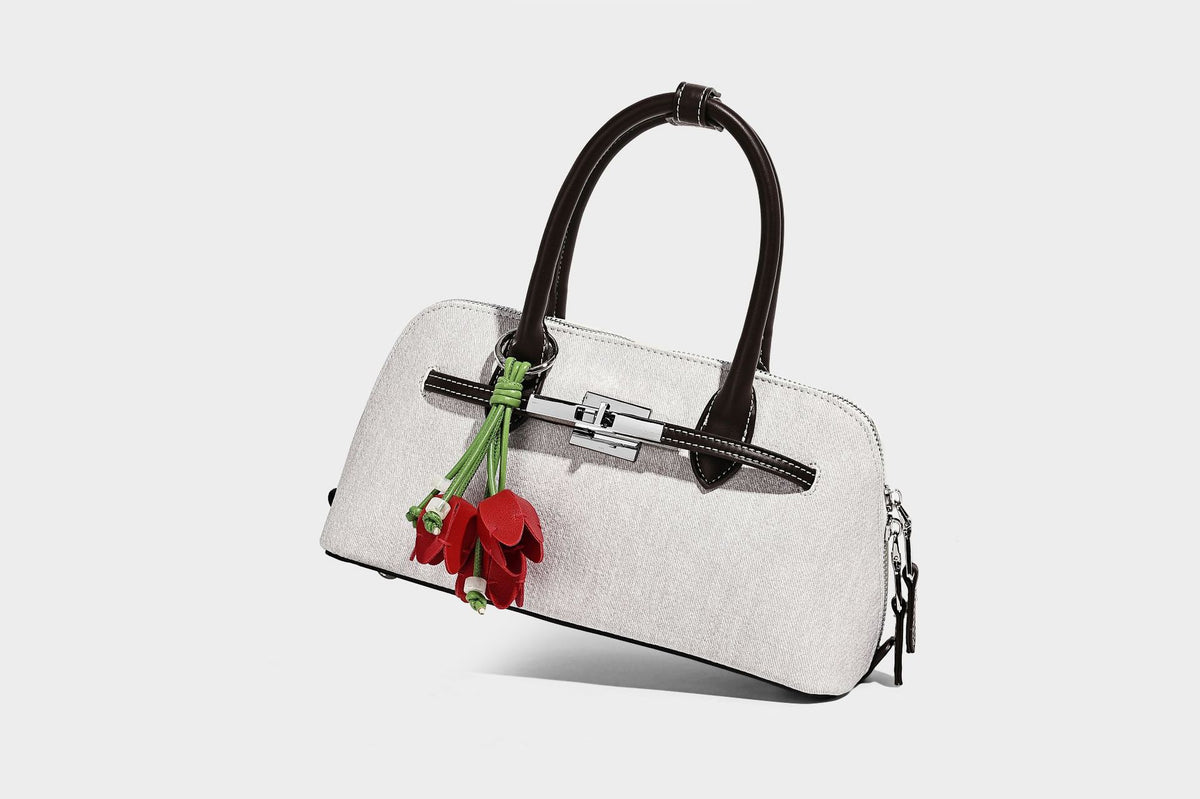 Compact structured satchel in light blue denim-look fabric with black leather-look trim, silver turn-lock closure, rolled
