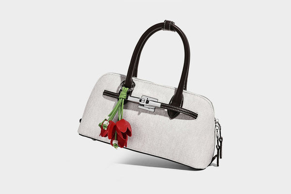 Compact structured satchel in light blue denim-look fabric with black leather-look trim, silver turn-lock closure, rolled