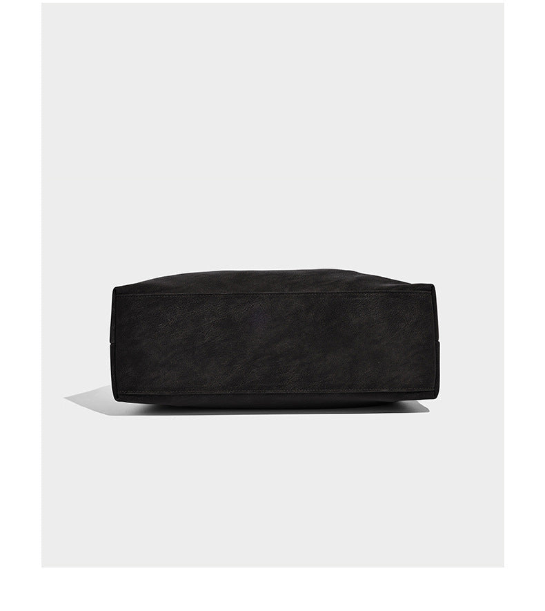 Slouchy oversized shoulder tote bag with matte textured finish, wrap-around buckle strap, and detachable front zip pouch