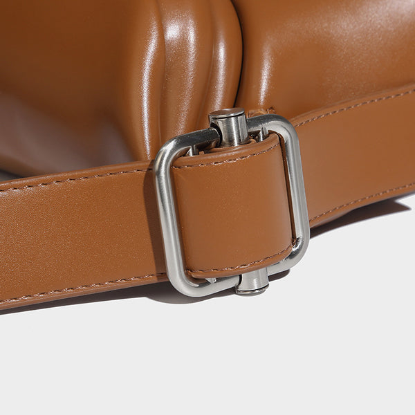Compact structured baguette shoulder bag with smooth leather-look finish, zip top, and adjustable silver-buckle strap, detail