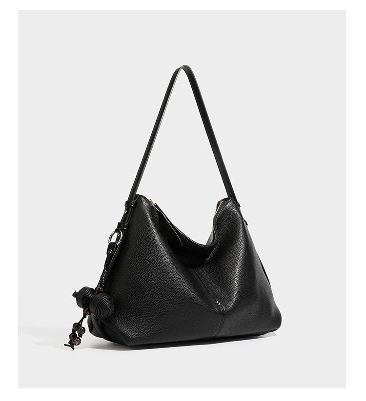 Slouchy hobo shoulder bag with pebbled leather-look finish, zip-top closure, gold-tone hardware, and hanging bead charm