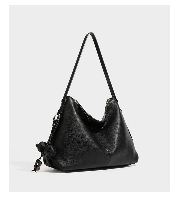 Slouchy hobo shoulder bag with pebbled leather-look finish, zip-top closure, gold-tone hardware, and hanging bead charm