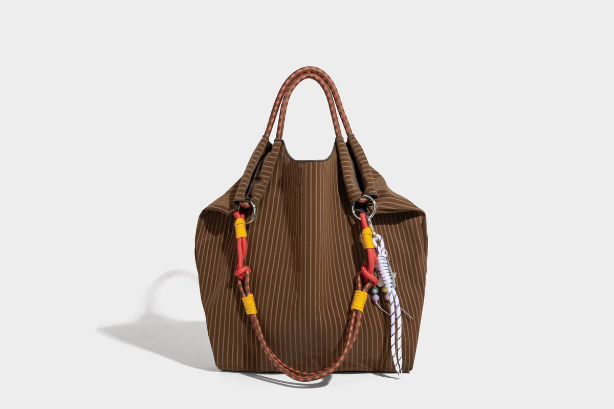 Slouchy pinstripe tote bag with braided rope handles, metal ring hardware, and colorful knotted rope charm, detail view 31