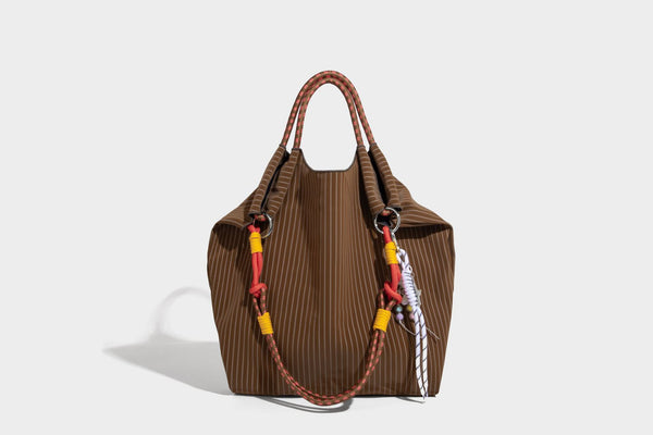 Slouchy pinstripe tote bag with braided rope handles, metal ring hardware, and colorful knotted rope charm, detail view 31