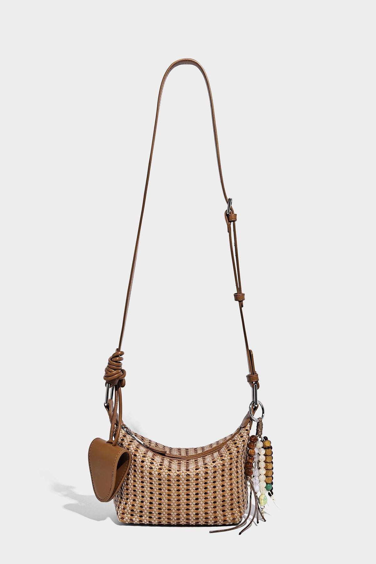 Woven crescent shoulder bag with leather-look knotted handle, zip top, attached mini pouch, and silver-tone hardware, detail