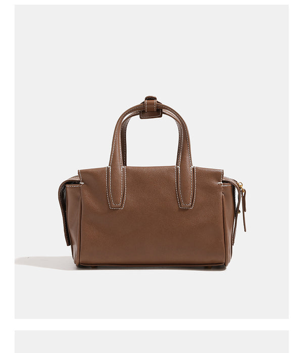 Compact structured satchel bag with dual top handles, gold-tone O-ring hardware, contrast topstitching, and detachable