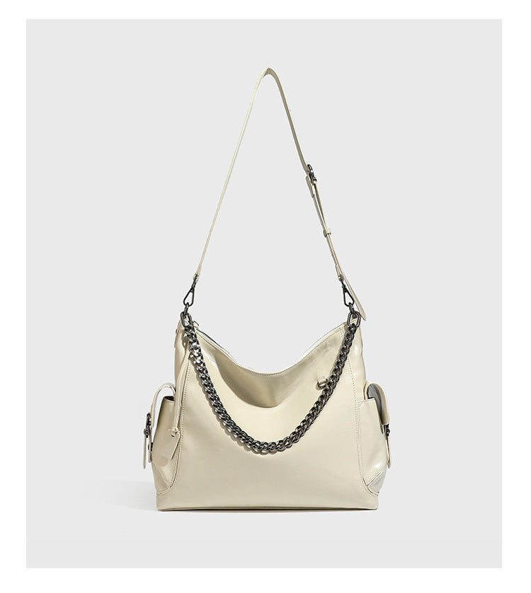 Slouchy hobo shoulder bag with glossy leather-look finish, silver-tone chain drape across front, side buckle pockets, and