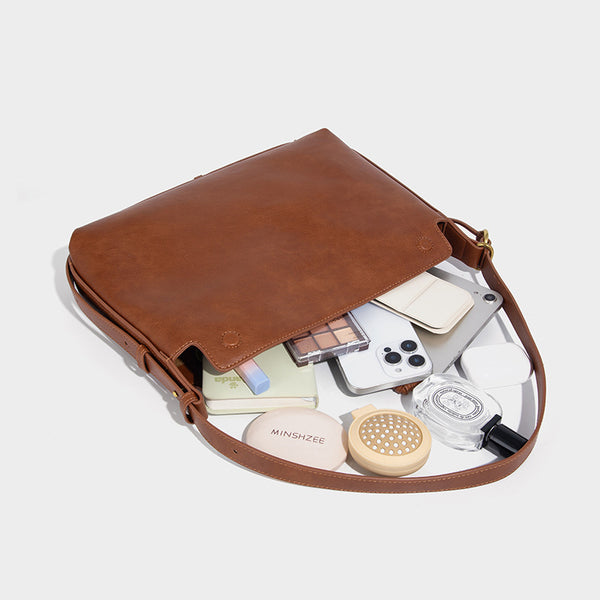 Slouchy brown leather-look shoulder bag with knotted drawcord tie closure, gold-tone ring hardware, and long adjustable