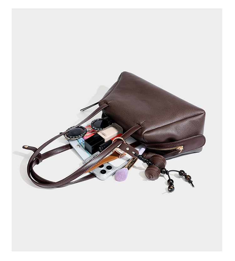 Structured trapezoid shoulder bag in dark brown pebbled leather-look finish with slim double straps, top zip closure, side