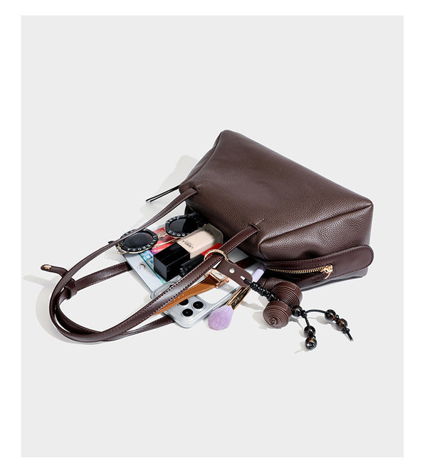 Structured trapezoid shoulder bag in dark brown pebbled leather-look finish with slim double straps, top zip closure, side