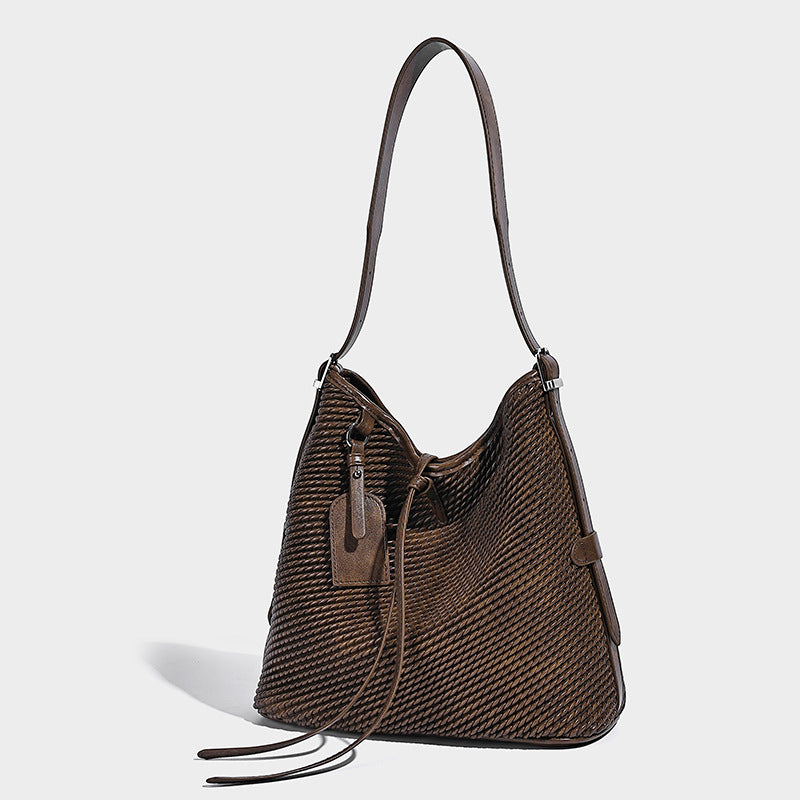 Large woven texture bucket shoulder bag with smooth leather-look trim, adjustable strap, and hanging tag detail, front view