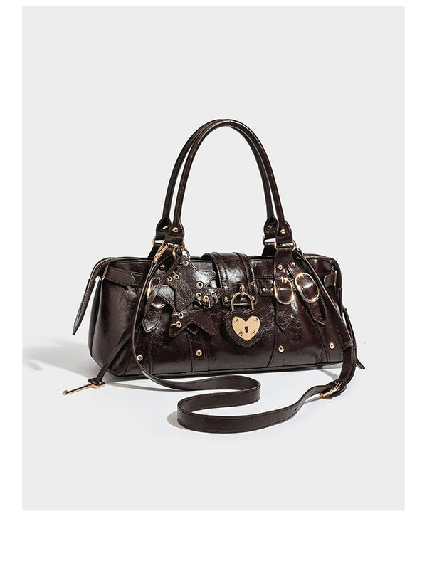 Glossy dark brown structured Boston satchel with heart-shaped lock charm, star pendant, rivet studs, multi-strap front panel