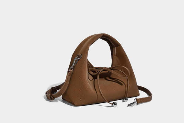 Pebbled matte trapezoid top-handle bag with drawstring bow closure, bead-tipped cords, silver-tone hardware, and detachable