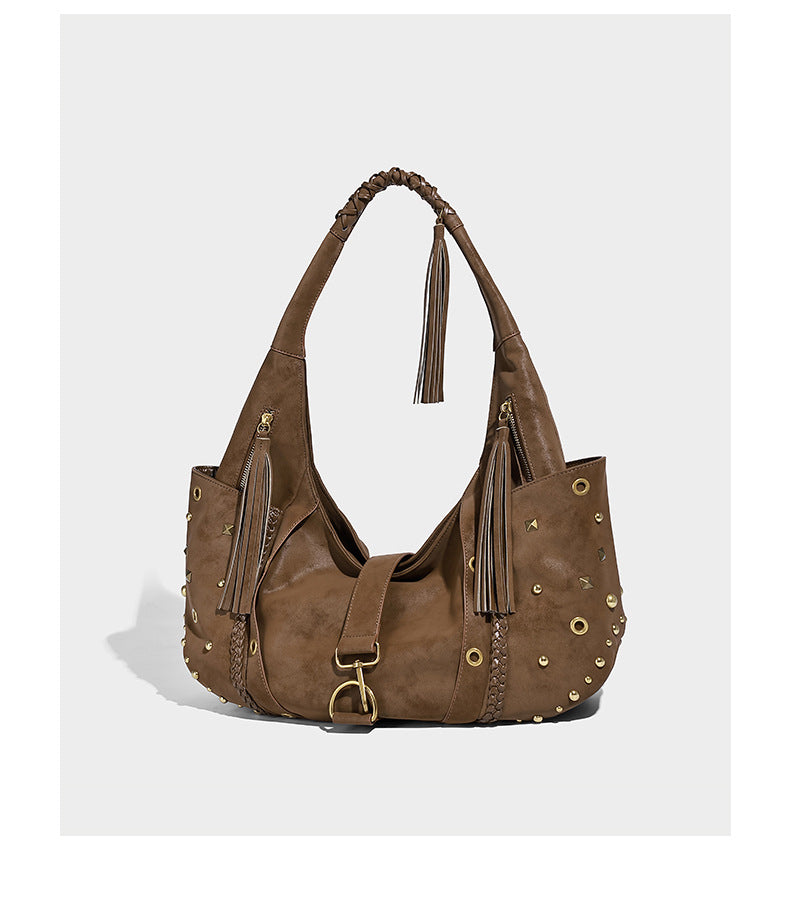 Slouchy crescent hobo bag in matte brown suede-like finish with gold-tone studs, grommets, braided top handle, tassel side