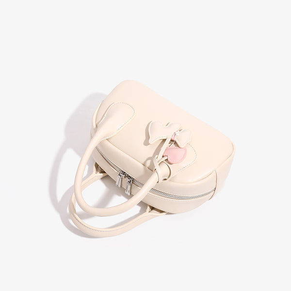 Mini-Handtasche in Kuppelform mit glatter Oberfläche in Lederoptik, zwei Tragegriffen, Reißverschluss oben, Beschlägen in Silberoptik und herabhängendem