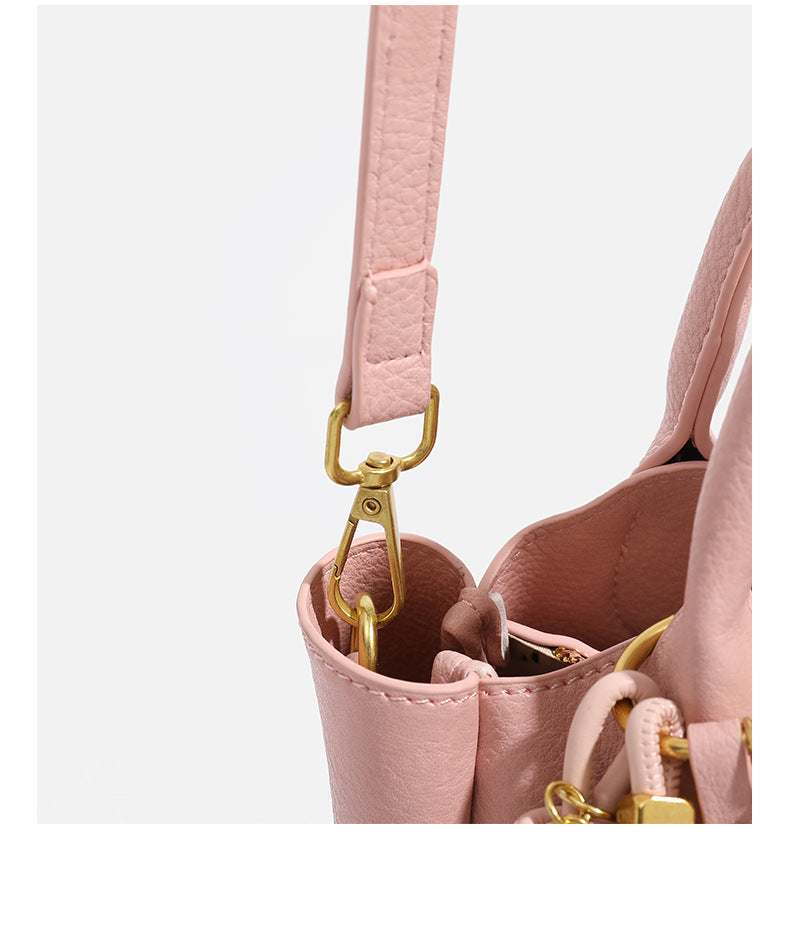 Small structured pebbled leather-look mini tote bag with gold-tone hardware, front toggle closure, knotted bear tassel charm