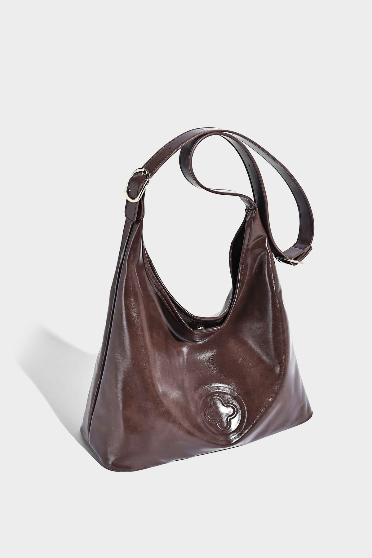 Glossy slouchy hobo shoulder bag with adjustable strap and embossed floral emblem, detail view 28