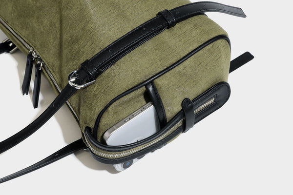 Olivgrüne Canvas-Schultertasche in Zylinderform mit schwarzen Trägern in Lederoptik, Reißverschluss oben und silberfarbenen Metallbeschlägen, Detailansicht