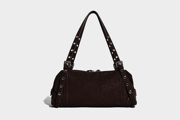 Weiche, zylinderförmige Schultertasche in Dunkelbraun mit silberfarbenen Riemen mit Ösen, Reißverschluss oben, seitlichen Schnallenbeschlägen und Quaste