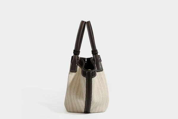 Cremefarbene geflochtene Tote-Bag mit dunkelbraunen Besätzen in Lederoptik, kontrastierenden weißen Nähten, zwei oberen Henkeln und abnehmbarem Schulter