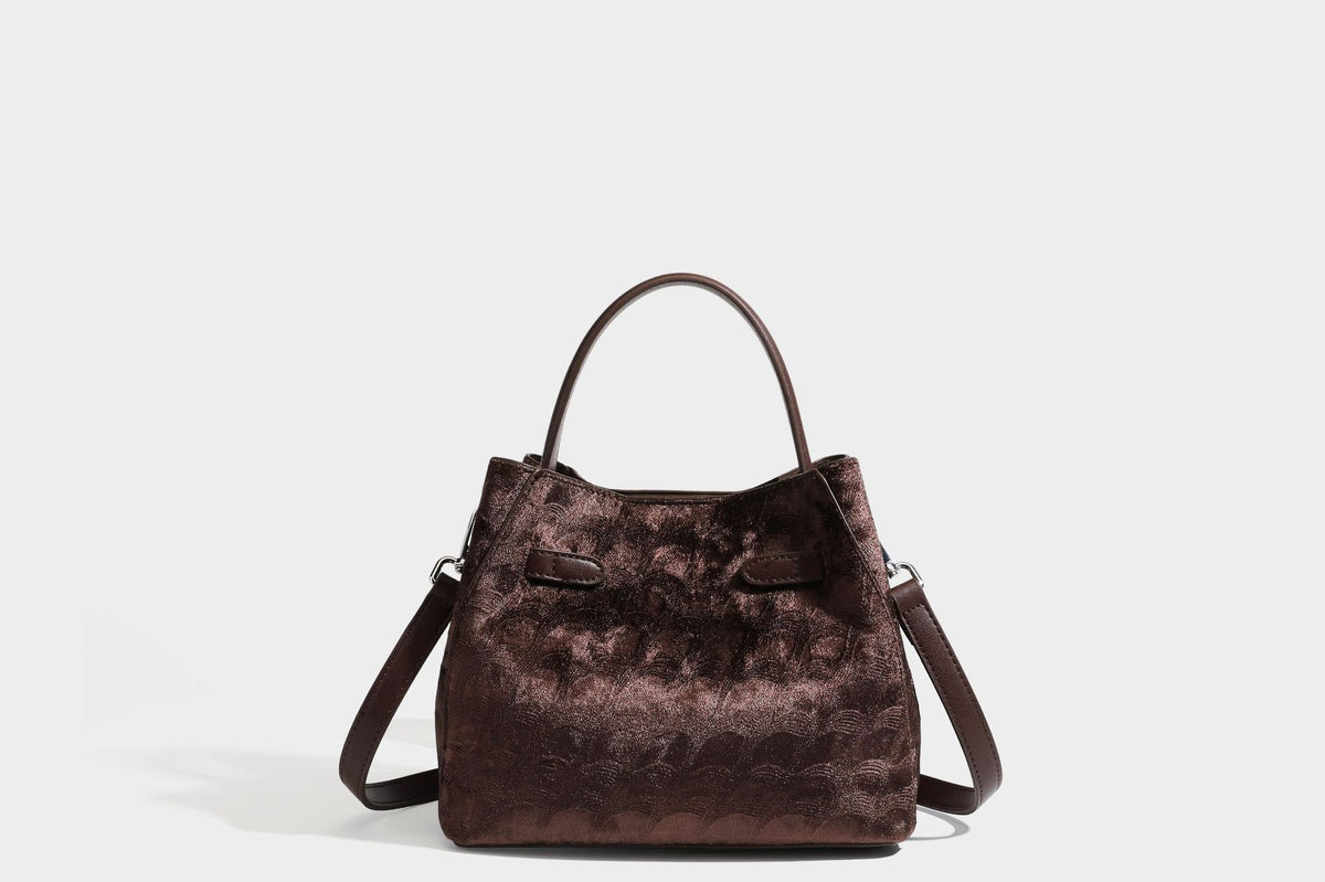 Small structured bucket satchel in embossed velvet-texture fabric with silver turn-lock hardware, rounded top handle, and