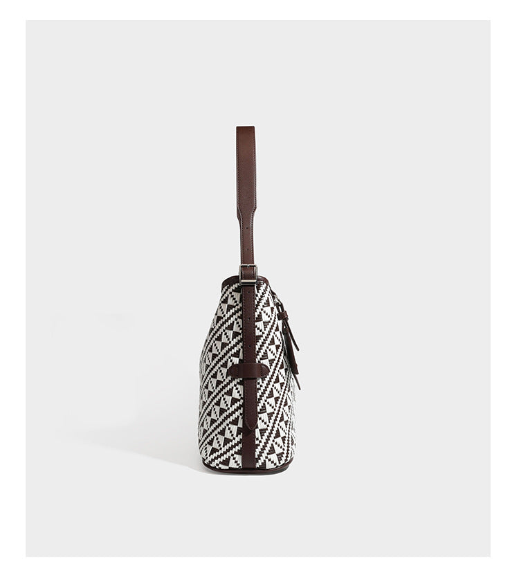 Woven geometric bucket shoulder bag in white and dark brown two-tone pattern with leather-look trim and drawstring top