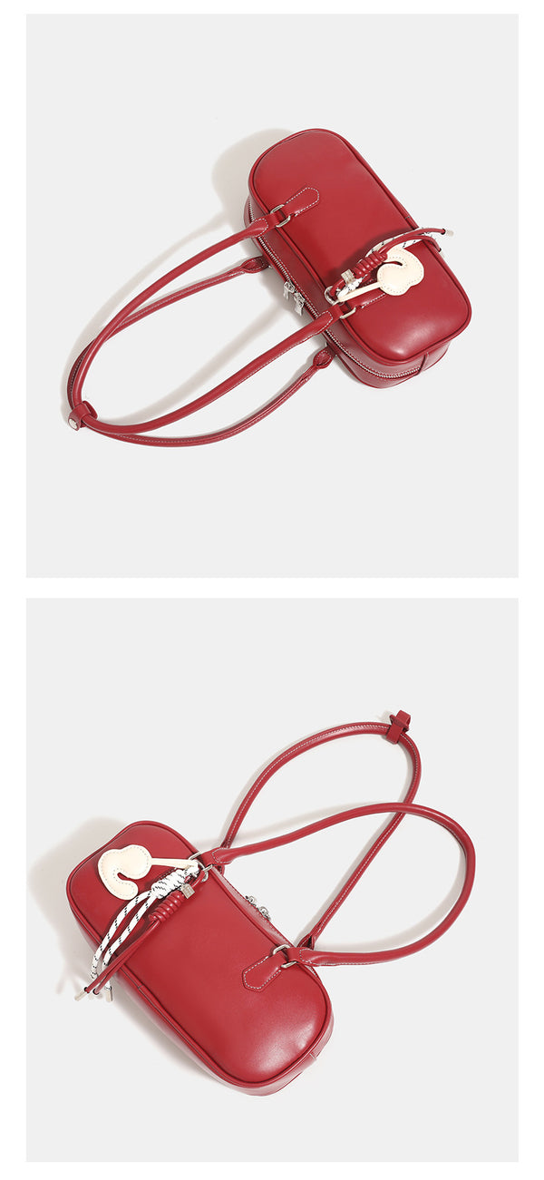 Compact rounded baguette shoulder bag with smooth leather-look finish, slim double straps, silver-tone zipper hardware, and