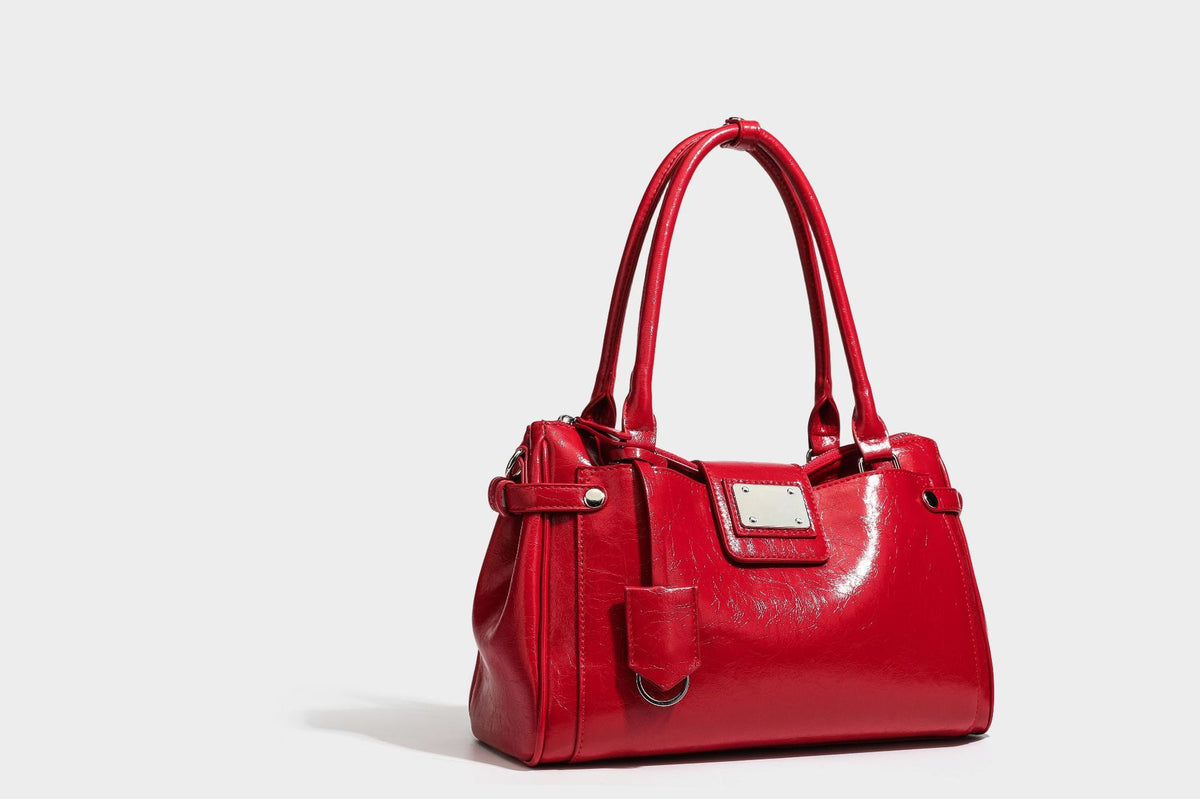 Structured glossy crinkled leather-look satchel with double top handles, front metal-plaque tab, silver-tone hardware, and