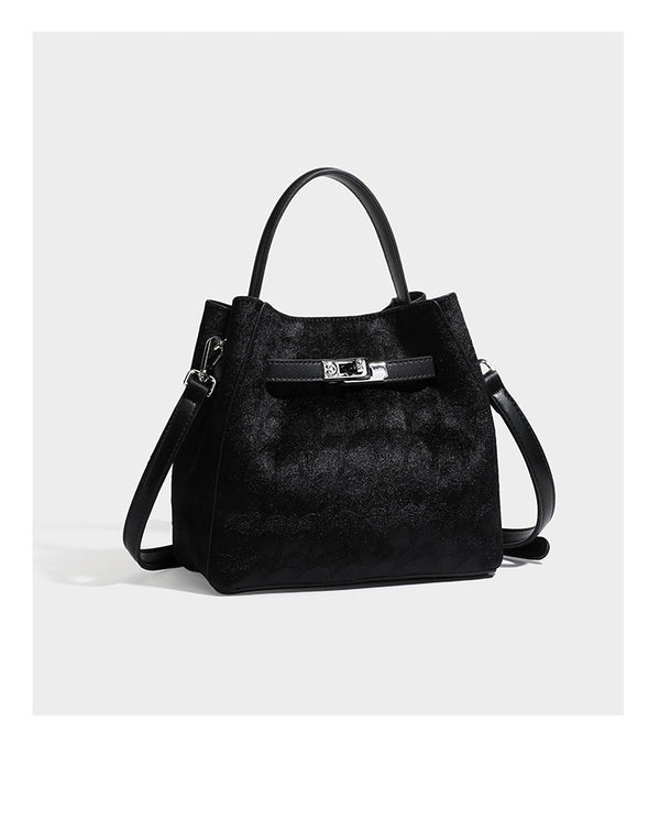 Small structured bucket satchel in embossed velvet-texture fabric with silver turn-lock hardware, rounded top handle, and