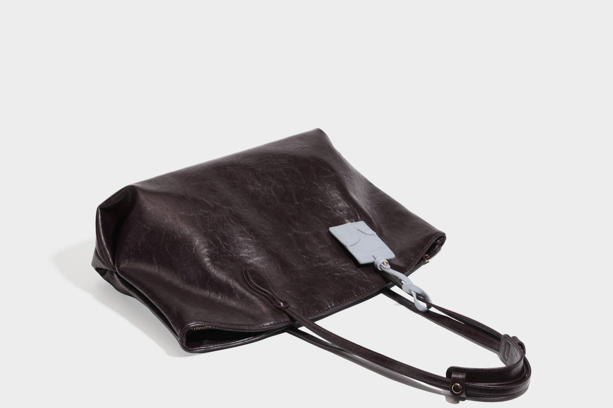 Übergroße, lässig fallende Tote-Bag aus glänzendem, geknittertem Lederimitat in dunklem Burgunderrot mit zwei langen Schulterriemen und kontrastierendem