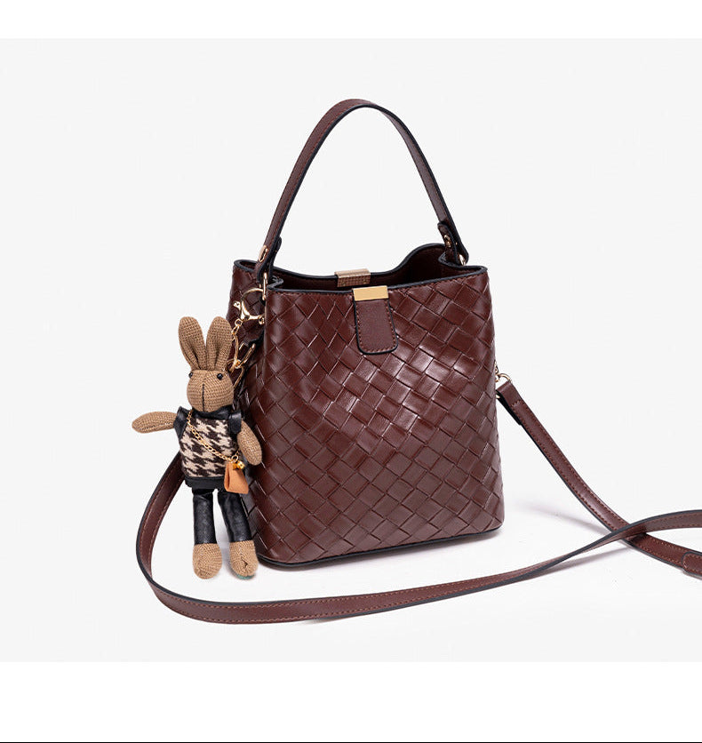 Brown woven-emboss leather-look bucket bag with short top handle, detachable crossbody strap, gold-tone hardware, and rabbit