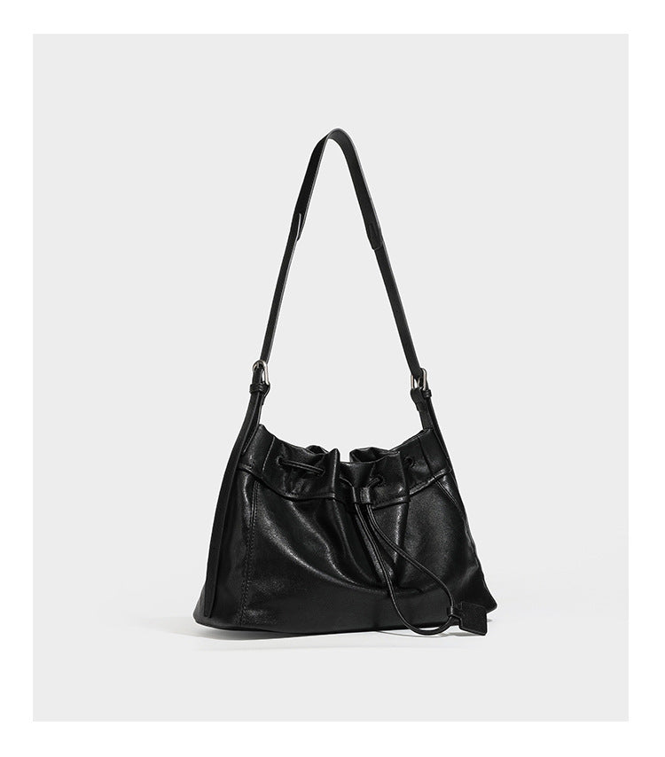 Slouchy drawstring bucket bag in dark brown leather-look finish with long adjustable shoulder strap and gathered tie closure