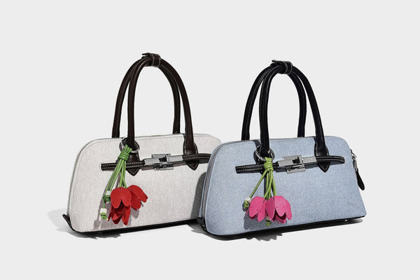 Compact structured satchel in light blue denim-look fabric with black leather-look trim, silver turn-lock closure, rolled