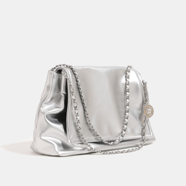 Soft trapezoidal chain-strap shoulder bag with foldover flap and circular logo medallion, detail view 2