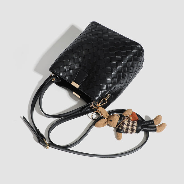 Black woven leather-look bucket bag with gold-tone clip closure, top handle, detachable shoulder strap, and knit bunny charm