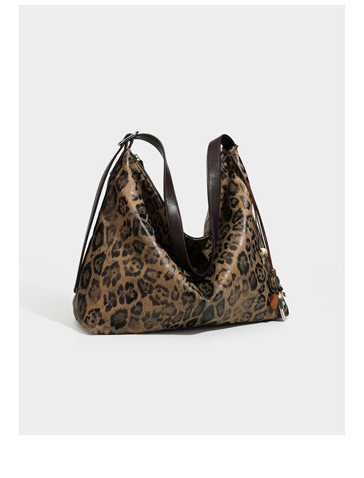 Slouchy leopard print hobo shoulder bag with glossy coated finish, top zipper closure, dark brown trim, and dangling charm