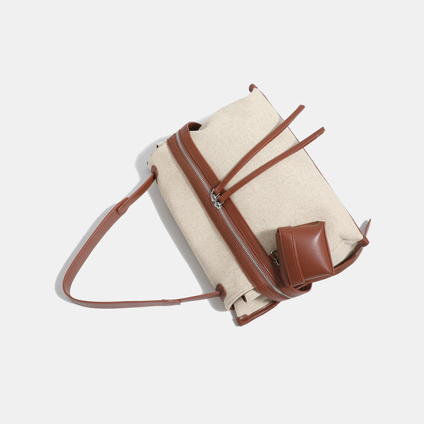 Off-white woven cotton-linen shoulder bag with brown leather-look trim, dual zip closure, long zipper pulls, front exterior