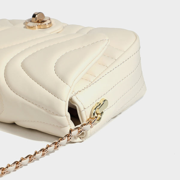 Compact cream quilted flap crossbody bag with wave stitching, gold-tone chain strap, and four-petal turn-lock clasp, detail
