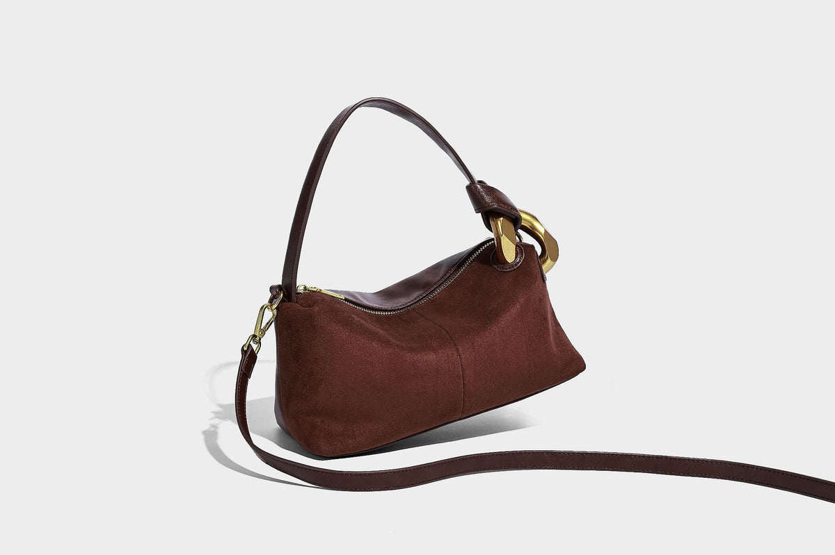 Kompakte Boston-Schultertasche in warmem Braun in Wildlederoptik mit glattem dunkelbraunem Besatz, übergroßen goldfarbenen Ringelementen und Reißverschluss oben
