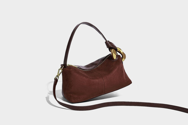 Kompakte Boston-Schultertasche in warmem Braun in Wildlederoptik mit glattem dunkelbraunem Besatz, übergroßen goldfarbenen Ringelementen und Reißverschluss oben