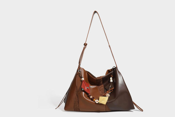 Two-tone black and brown leather-look slouchy shoulder bag with beaded tassel charm and silver-tone hardware, detail view 19